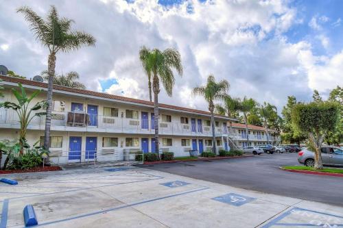 a building with blue doors and palm trees in a parking lot at Motel 6-Chino, CA - Los Angeles Area in Chino