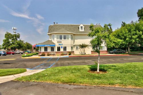 a building with a tree in a parking lot at Motel 6-Sacramento, CA - South Sacramento and Elk Grove in Sacramento