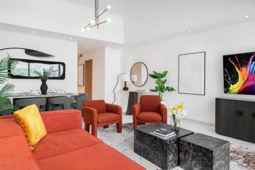a living room with a red couch and two orange chairs at Private Pool Paradise Villa! Dubai Mall in a Flash! Complimentary Full Mid-Stay Refresh for 1 week stay in Dubai