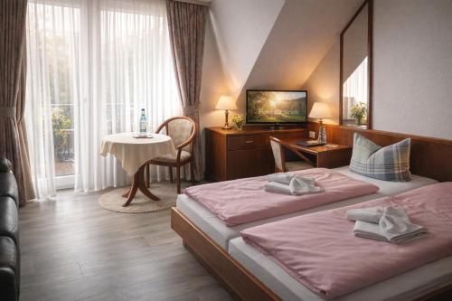 ein Hotelzimmer mit zwei Betten und einem Tisch in der Unterkunft Hotel zur Struth in Eschwege