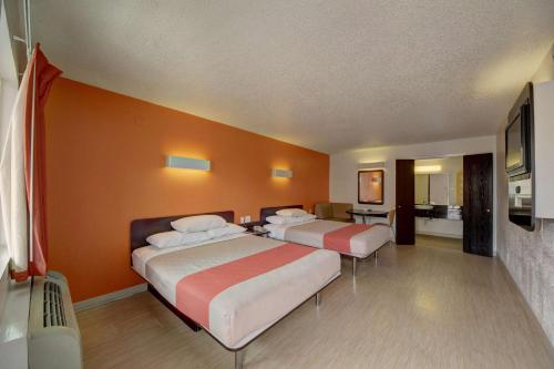 two beds in a room with orange walls at Motel 6-San Antonio, TX - Downtown - Market Square in San Antonio