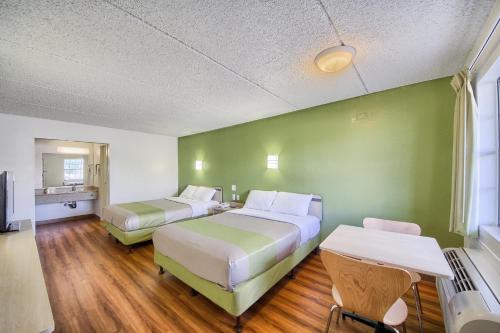 two beds in a room with green walls and wooden floors at Motel 6-San Antonio, TX - Northwest Medical Center in San Antonio