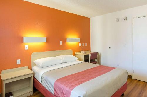 a bedroom with a bed with an orange wall at Motel 6- Denver, CO Downtown in Denver