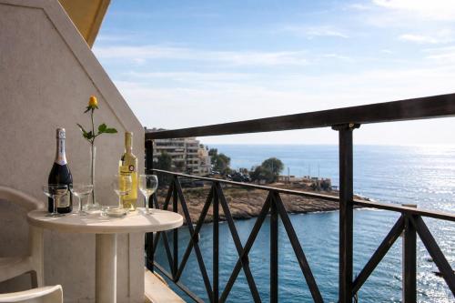 a table with wine bottles and glasses on a balcony at Queens Leriotis Hotel in Piraeus