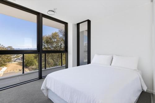 a bedroom with a white bed and large windows at Surfers paradise Luxury 2BR River View Retreat in Gold Coast