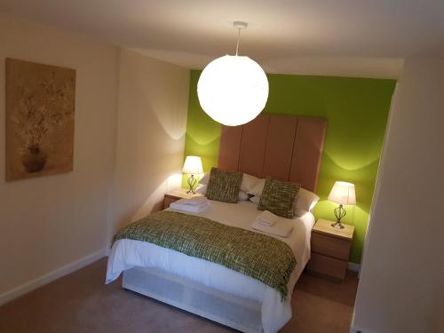 a bedroom with a bed with green walls and a lamp at Baltic Quays Newcastle Upon Tyne in Newcastle upon Tyne