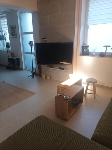 ein Wohnzimmer mit Flachbildfernseher und Tisch in der Unterkunft La longère Saint-Eloi 