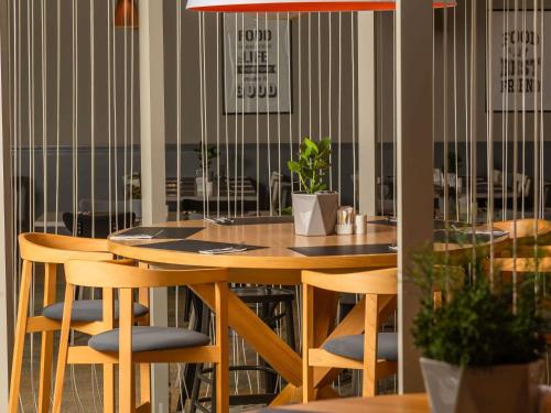a dining room with a wooden table and chairs at Novotel Kraków City West in Kraków