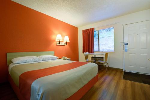 シータックにあるモーテル 6 シアトル エアポートのオレンジ色の壁のベッドが備わるホテルルームです。