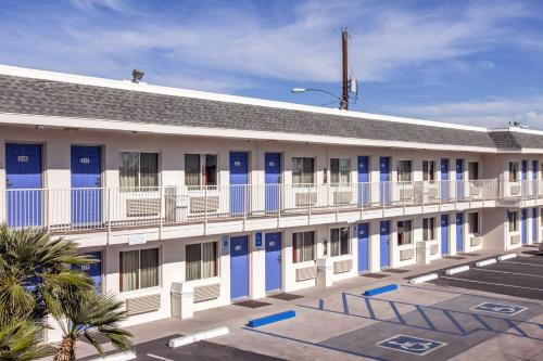 a building with blue and white doors and palm trees at Motel 6-Phoenix, AZ - Airport - 24th Street in Phoenix