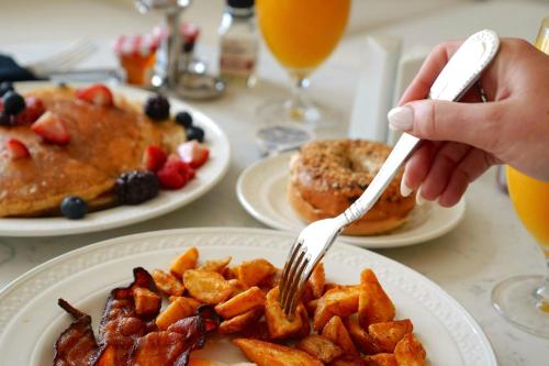 eine Person, die eine Gabel über einen Teller mit Frühstücksspeisen hält in der Unterkunft The Vinoy Resort & Golf Club, Autograph Collection in St Petersburg