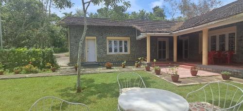 ein kleines Haus mit einem Hof, auf dem ein Tisch steht, und einem Garten in der Unterkunft Nadhi Teera Riverside Stay in Kushālnagar