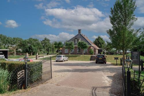 a house with cars parked in front of a driveway at B&B Stations Koffiehuis in Molkwerum