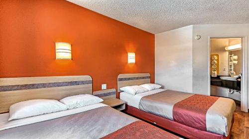 a room with two beds and an orange wall at Motel 6-Killeen, TX in Killeen