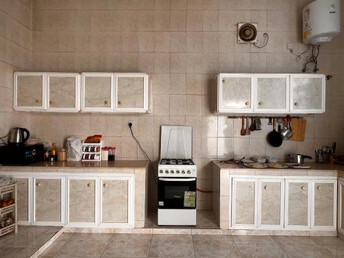 kuchnia z białymi szafkami i kuchenką w obiekcie Amour Hostel w mieście As-Sib