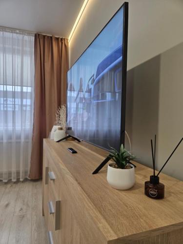 ein Wohnzimmer mit einem großen Flachbild-TV auf einer Kommode in der Unterkunft Studio IT on Tumo in Plungė