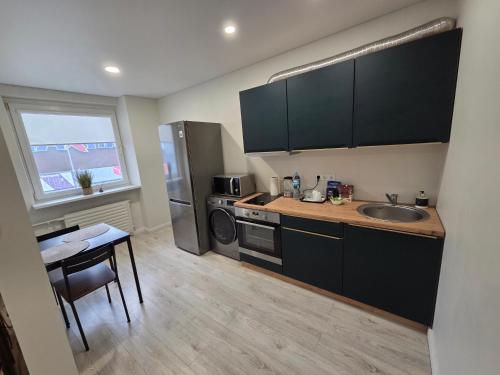 eine Küche mit einem Waschbecken und einem Tisch mit einem Tisch in der Unterkunft Studio IT on Tumo in Plungė