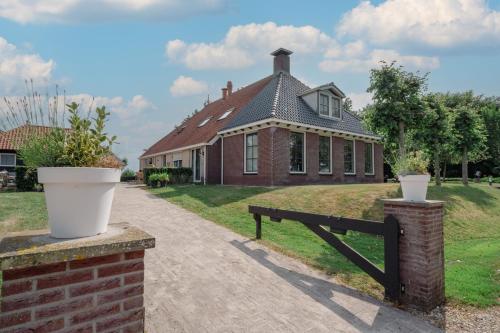 a brick house with a fence in front of it at B&B Stations Koffiehuis in Molkwerum