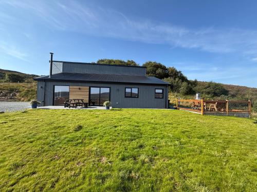 Ein schwarzes Haus auf einem grünen Feld in der Unterkunft Luxury 3 Bedroom House - Stag Moor House in Portree