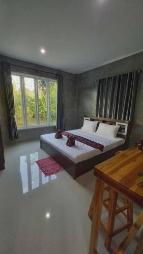 a bedroom with two beds and a table and windows at Pool Villa Rai View Khao in Ban Klang