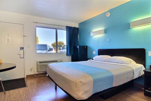 a bedroom with a large bed with a blue wall at Motel 6-Carlsbad, NM in Carlsbad
