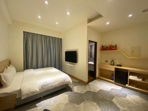 a bedroom with a bed and a flat screen tv at Yunfeng Hotel 雲峰精品文旅 in Jinning