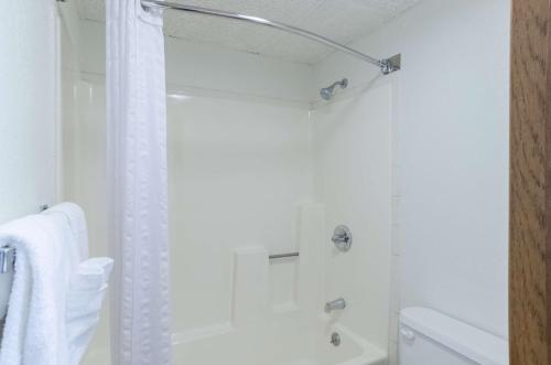 a white bathroom with a shower with a shower curtain at Baymont by Wyndham Gillette in Gillette