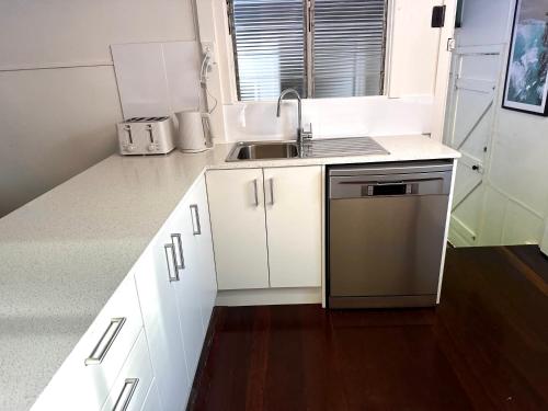 a small kitchen with white cabinets and a sink at Little Ray on Sunshine. Hamptons style beachhouse in Woorim