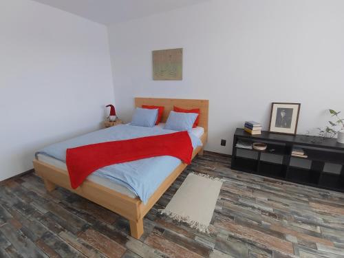 a bedroom with a bed with a red blanket on it at Apartmán Emma Volary in Volary