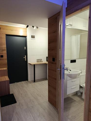 een badkamer met een zwarte deur en een wastafel bij Pokoje w Łomiankach Warszawa in Łomianki