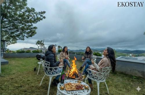 een groep vrouwen die rond een vuur zitten bij EKOSTAY - Skyfall Mist Villa in Ooty