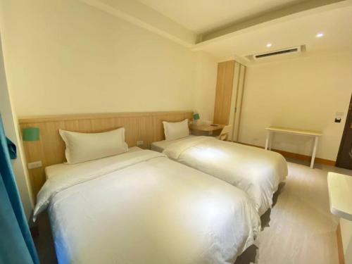 two beds in a room with white sheets at Yunfeng Hotel 雲峰精品文旅 in Jinning
