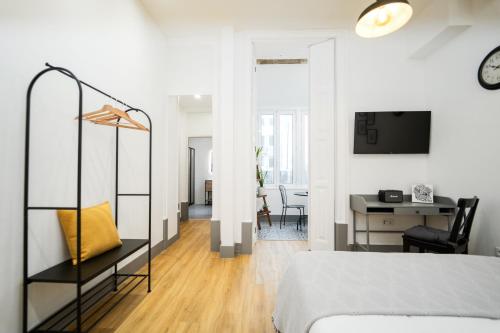 a white room with a bed and a desk and a table at Bairro Novo - Alojamento Local in Figueira da Foz