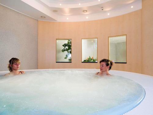 twee vrouwen in een bad in een badkamer bij Novotel Hannover in Hannover