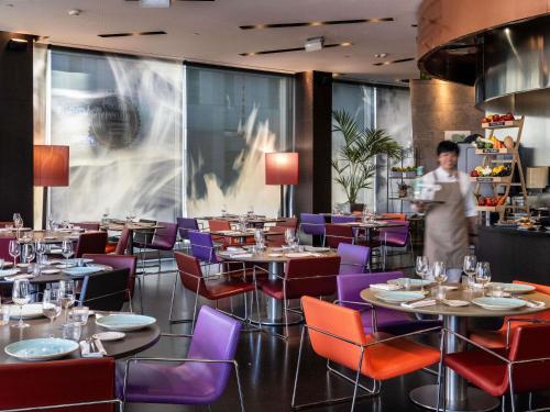 een man in een restaurant met tafels en stoelen bij Novotel Barcelona City in Barcelona