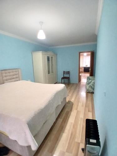 a bedroom with a white bed and a wooden floor at уют in Rustavi