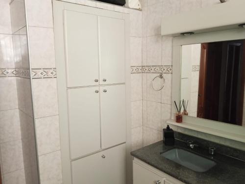 un bagno bianco con lavandino e specchio di Carvalho Apê Centro I Poços de Caldas a Poços de Caldas