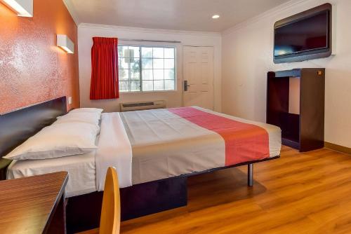 a bedroom with a large bed with a colorful blanket at Motel 6 Garden Grove in Anaheim