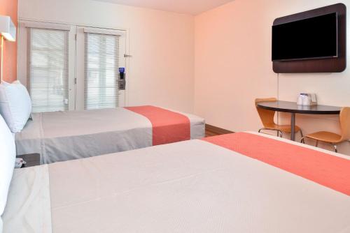 a hotel room with two beds and a table and a tv at Days Inn by Wyndham Brawley in Brawley