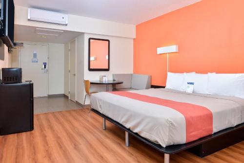 a bedroom with a large bed with an orange wall at Days Inn by Wyndham Brawley in Brawley