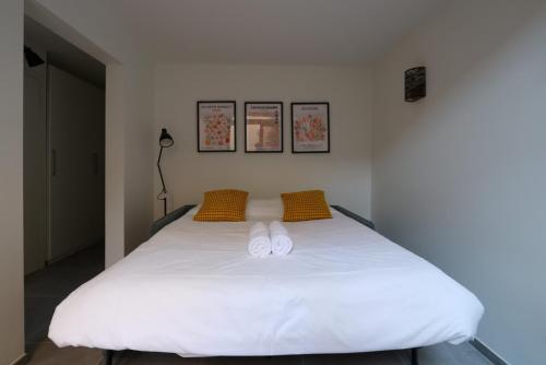 ein Schlafzimmer mit einem weißen Bett und zwei gelben Kissen in der Unterkunft Nümad Suites in Nizza