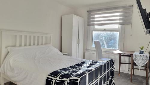 a bedroom with a bed and a desk and a window at CityStay London in London