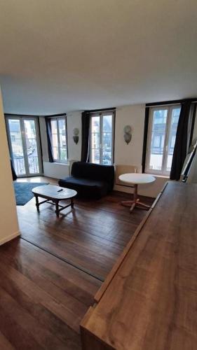 a living room with a couch and tables and windows at Harfleur Studio in Harfleur