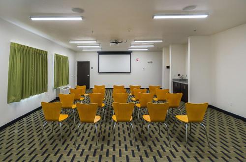 a conference room with yellow chairs and a screen at Motel 6-South Bend, IN - Mishawaka in South Bend