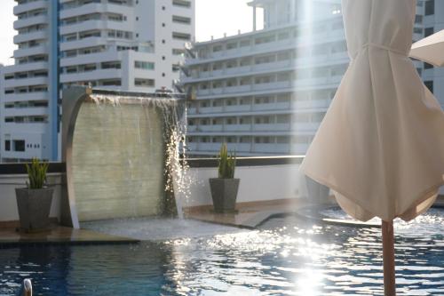 a swimming pool with a fountain in a city at Patong Condo Tub, Roof Pool & 2-min to Beach in Patong Beach