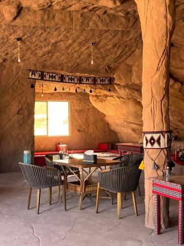 a dining room with tables and chairs and a stone wall at Ajyad Rum Camp in Wadi Rum