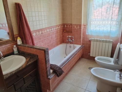 a bathroom with a tub and a toilet and a sink at Casa Seán in Boiro