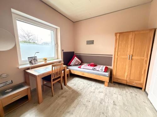 a small room with a desk and a bed and a window at Pension & Gästehaus Legden in Legden