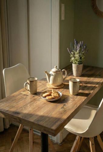 een houten tafel met twee kopjes en een theepot erop bij Bois Émeraude in Aix-les-Bains