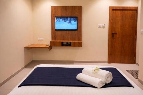 een kamer met 2 handdoeken op een bed en een televisie bij Relax Kurla Dormitory in Mumbai